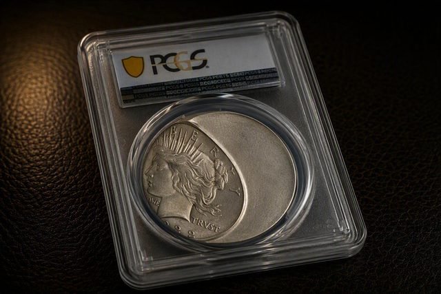 Peace Dollar von 1922 im PCGS-Halter mit deutlicher Fehlprägung: Das Münzbild sitzt zur linken Seite verschoben, rechts bleibt eine große glatte Fläche ohne Prägung und ohne Rand